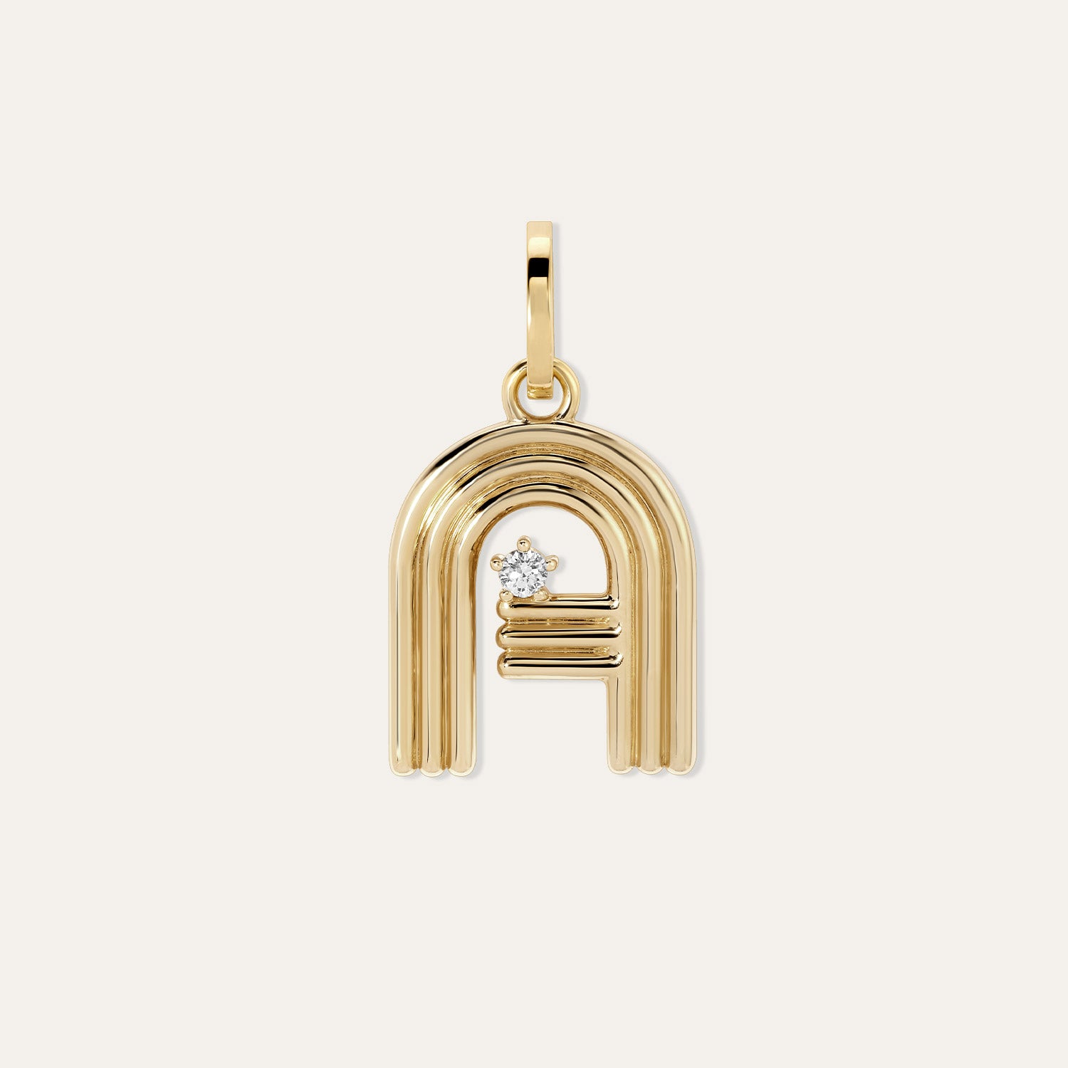 A gold charm featuring a letter 'A' design with a small diamond accent, shown on a light cream background.