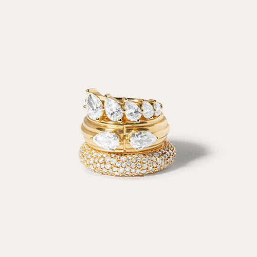 Three gold rings with diamonds stacked on top of each other with a cream background.